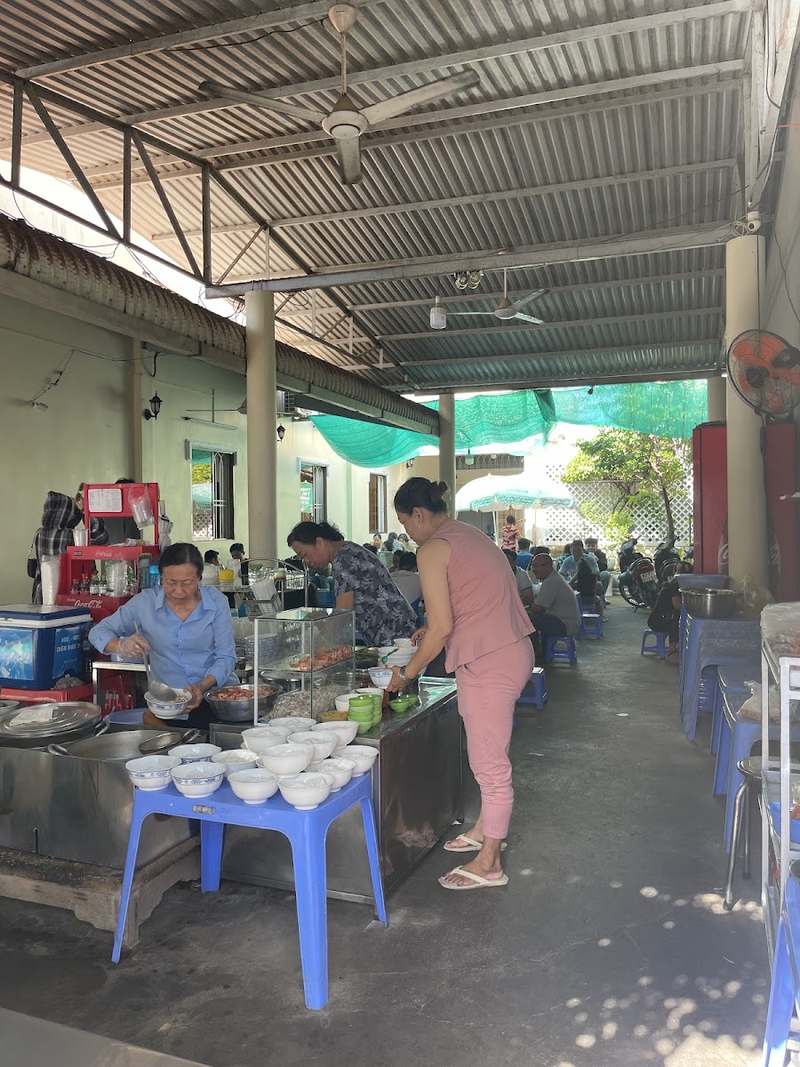 Mái che rộng với quầy nấu và bàn ghế nhựa xanh